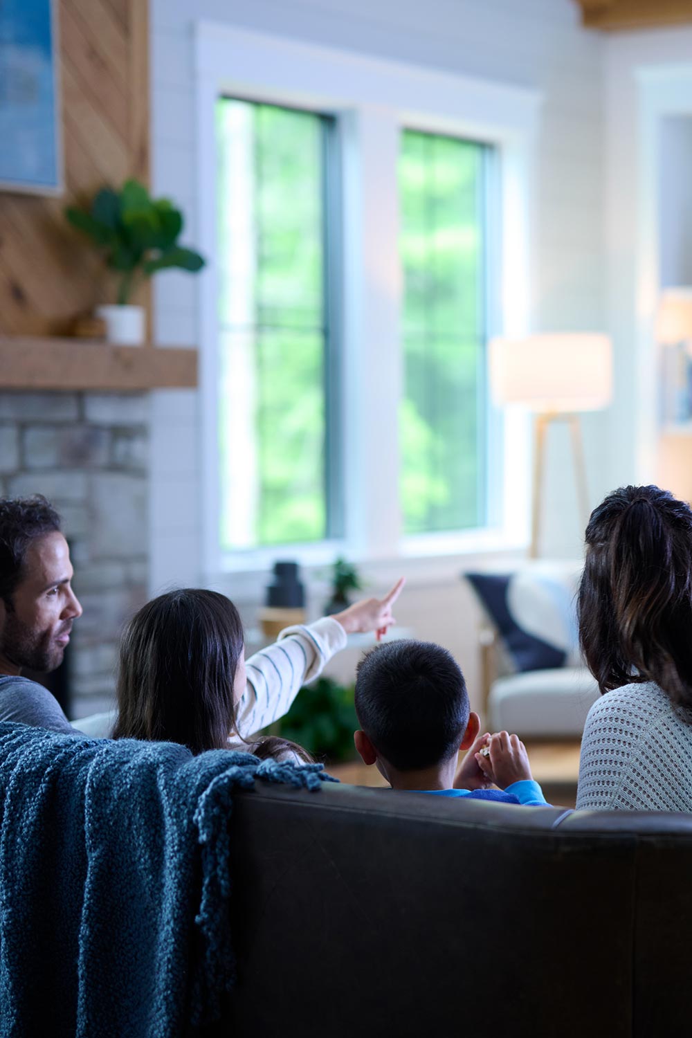 Family sitting together on a sofa in a bright living room with large windows